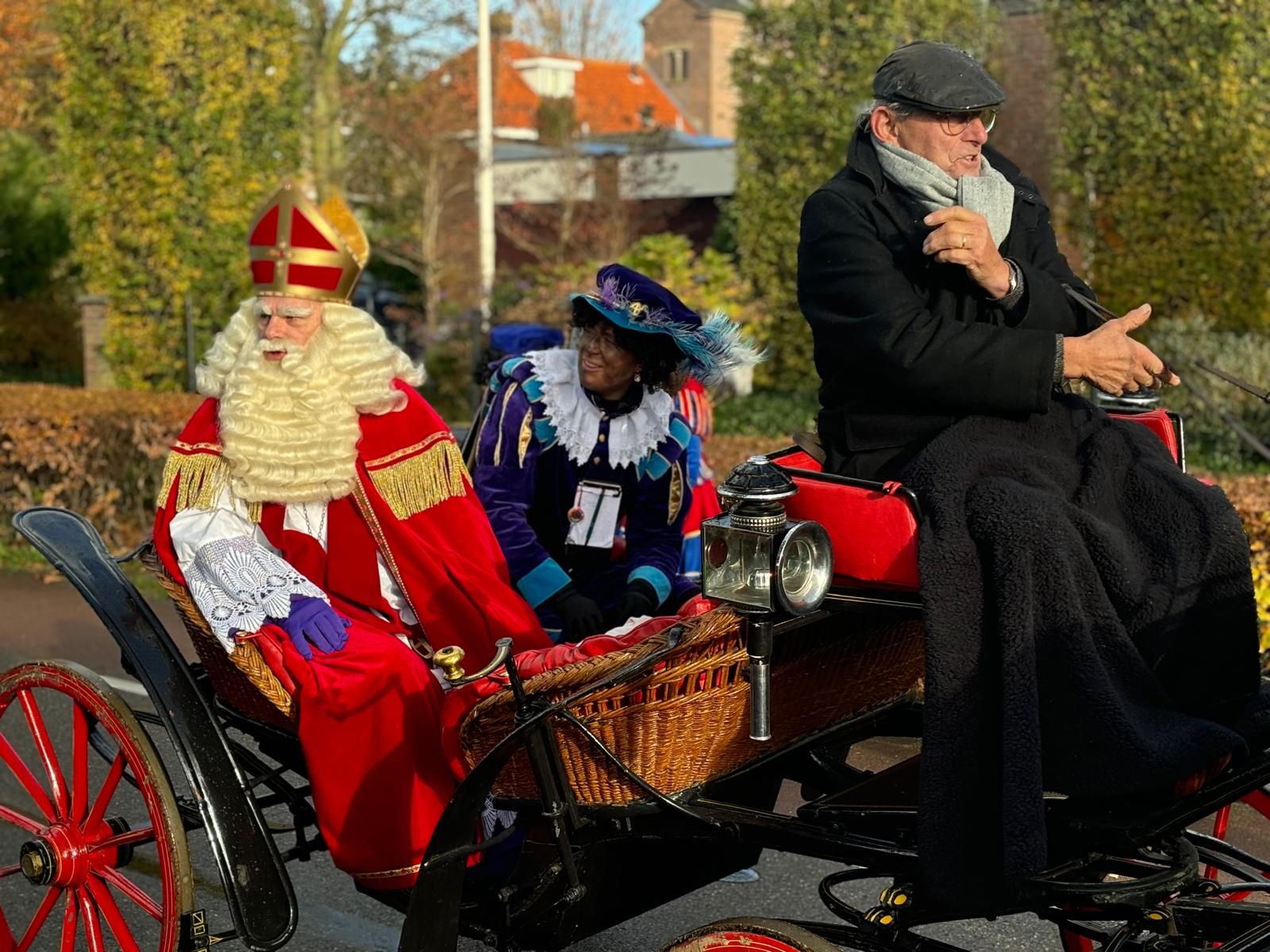 Sinterklaas en een piet zitten samen in de koets